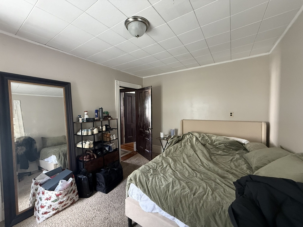 4 Barstow Street Boston, MA 02134 - Photo 13 of 21 a bed sitting in a bedroom next to a window with tv and couch