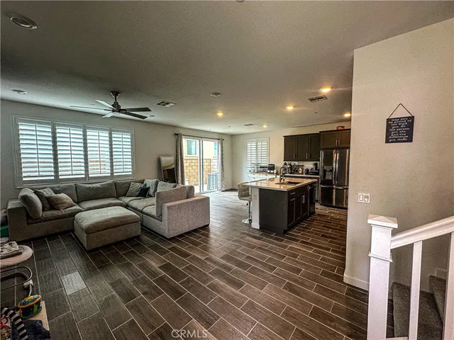 a living room with furniture kitchen view and a wooden floor