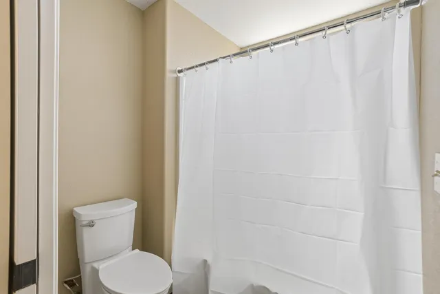 a white toilet sitting next to a shower