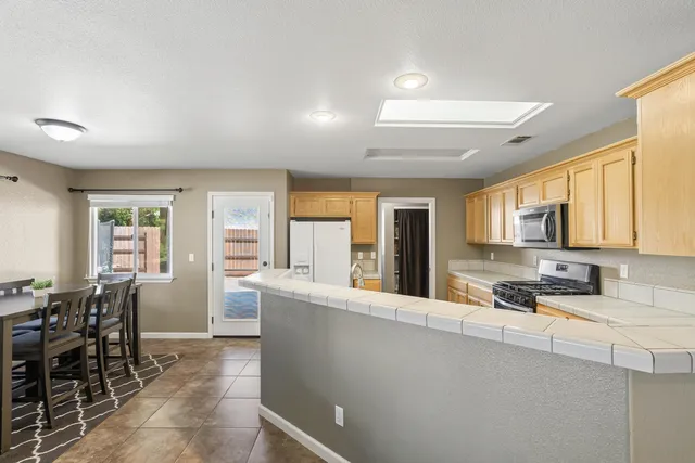 a large kitchen with kitchen island a large window in a dining table and chairs