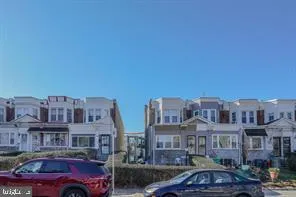 a front view of a building with lot of cars and trees