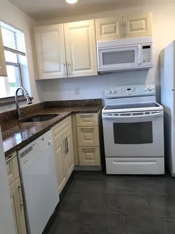 a kitchen with granite countertop white cabinets and white stainless steel appliances