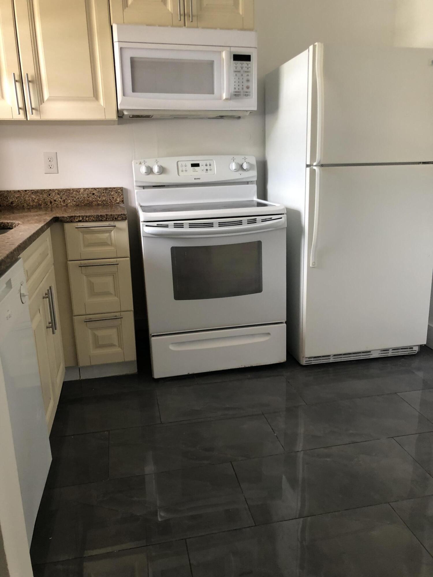 6850 Royal Palm Boulevard, Unit 104G Margate, FL 33063 - Photo 7 of 17 a kitchen with granite countertop white cabinets and white stainless steel appliances