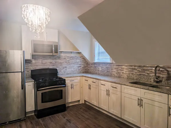 a kitchen with granite countertop white cabinets stainless steel appliances and a counter space
