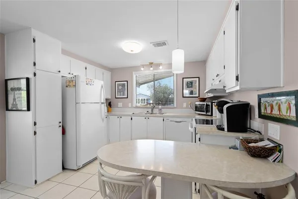 a kitchen with stainless steel appliances a stove a refrigerator a sink a dining table and chairs