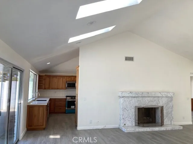 a living room with stainless steel appliances furniture a fireplace and a kitchen view