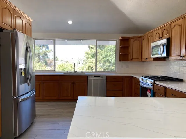 a kitchen with stainless steel appliances granite countertop a refrigerator a sink dishwasher a stove and a refrigerator with wooden floor