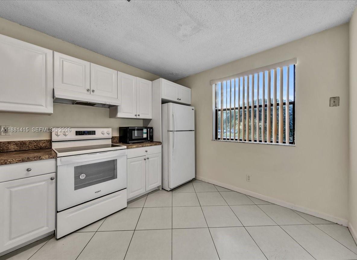 5661 Riverside Drive, Unit 101B7 Coral Springs, FL 33067 - Photo 15 of 49 a kitchen with white cabinets and white appliances