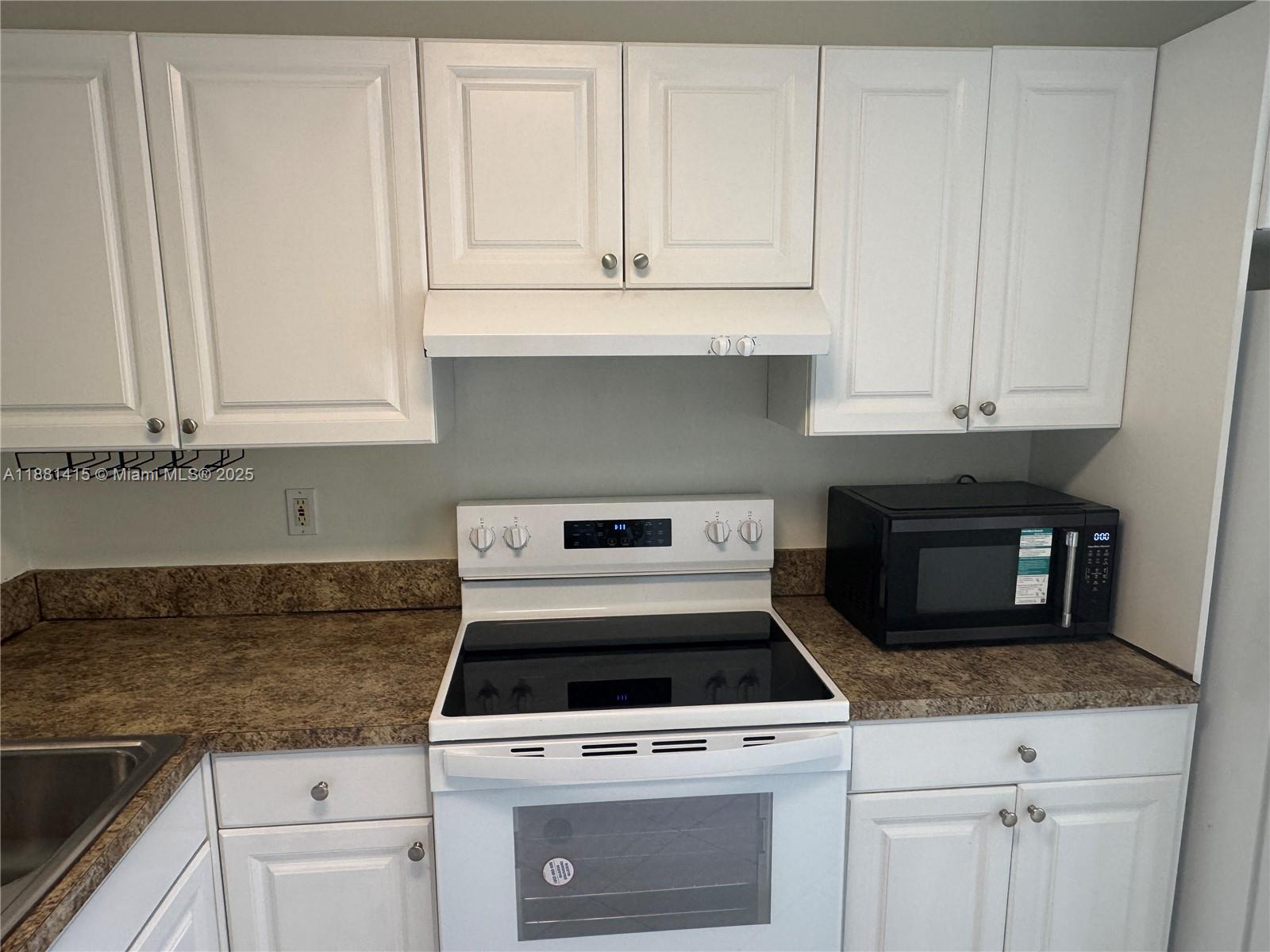 5661 Riverside Drive, Unit 101B7 Coral Springs, FL 33067 - Photo 16 of 60 a kitchen with granite countertop white cabinets and white appliances