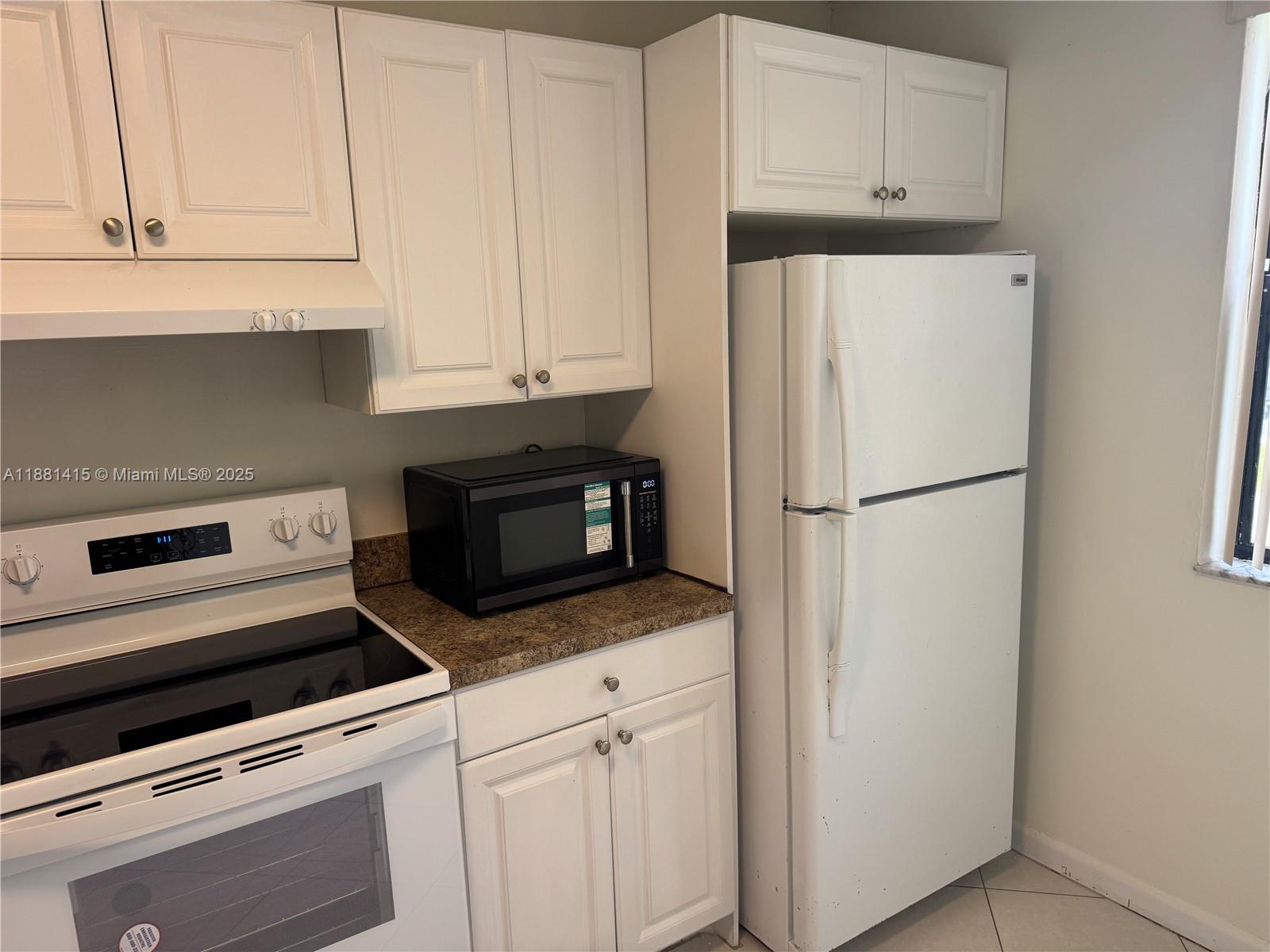 5661 Riverside Drive, Unit 101B7 Coral Springs, FL 33067 - Photo 17 of 60 a kitchen with granite countertop white cabinets and refrigerator