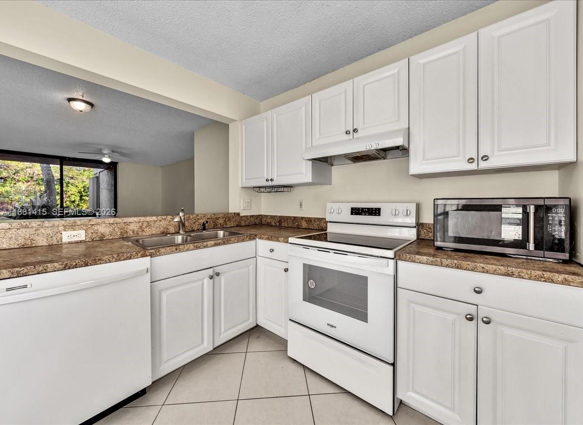 5661 Riverside Drive, Unit 101B7 Coral Springs, FL 33067 - Photo 20 of 49 a kitchen with white cabinets appliances and a sink