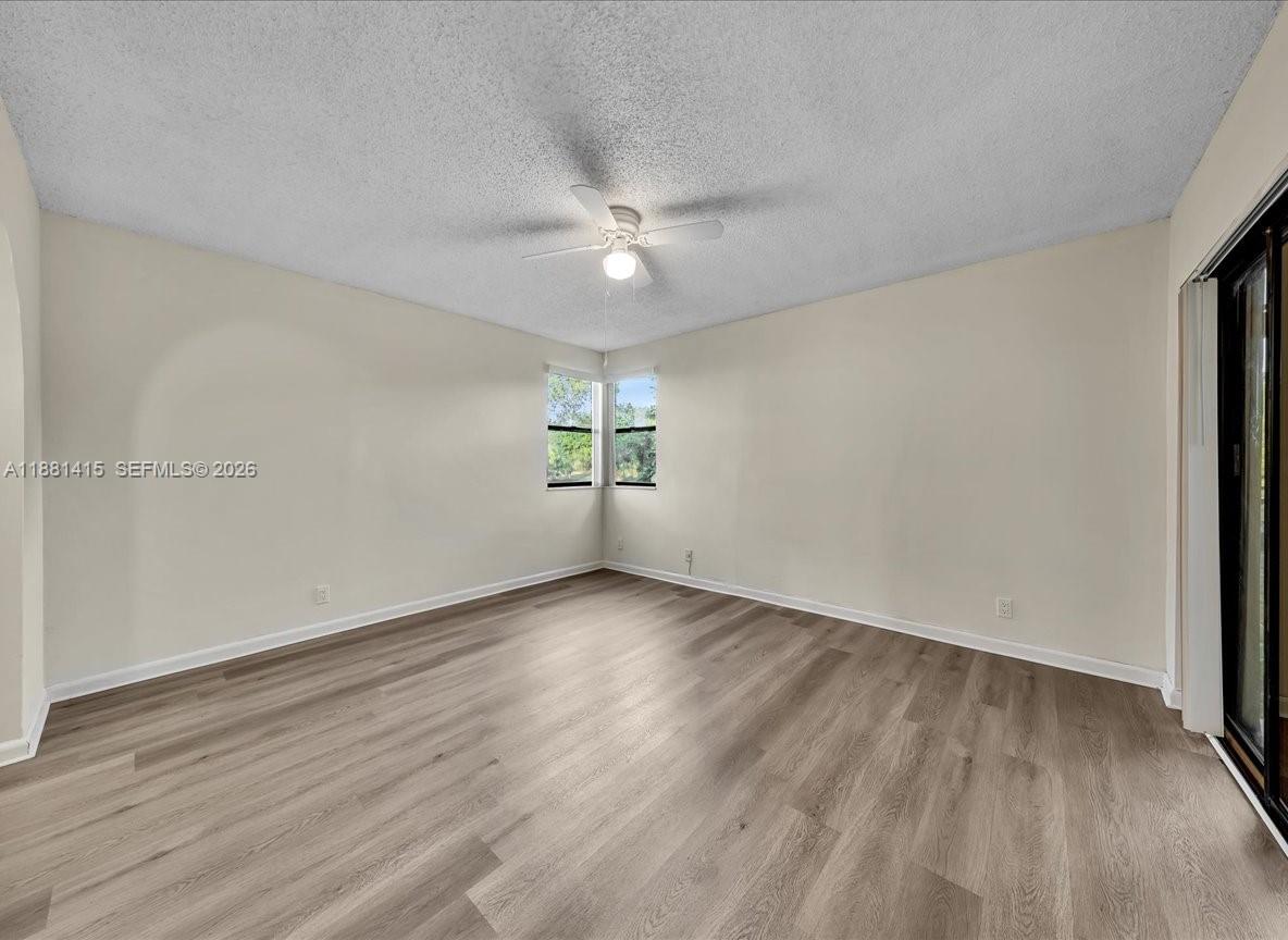 5661 Riverside Drive, Unit 101B7 Coral Springs, FL 33067 - Photo 22 of 49 an empty room with wooden floor ceiling fan and windows