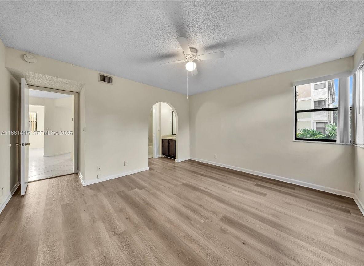 5661 Riverside Drive, Unit 101B7 Coral Springs, FL 33067 - Photo 23 of 49 a view of an empty room with wooden floor and a window