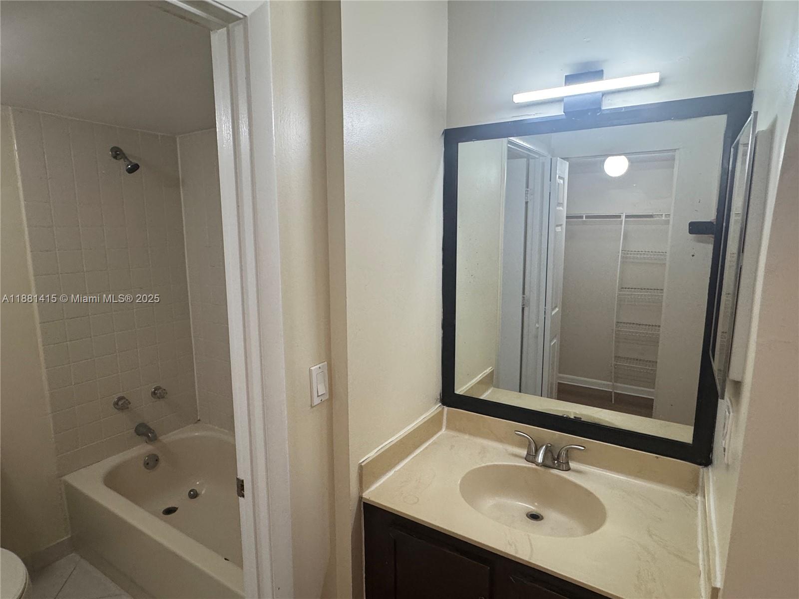 5661 Riverside Drive, Unit 101B7 Coral Springs, FL 33067 - Photo 28 of 60 a bathroom with a sink tub and mirror