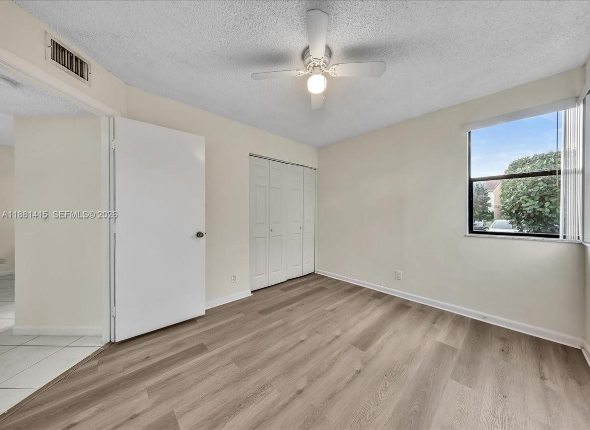 5661 Riverside Drive, Unit 101B7 Coral Springs, FL 33067 - Photo 39 of 49 an empty room with wooden floor chandelier fan and windows