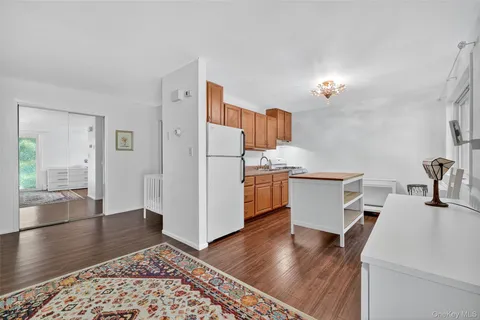 a living room with stainless steel appliances kitchen island hardwood floor and a sink