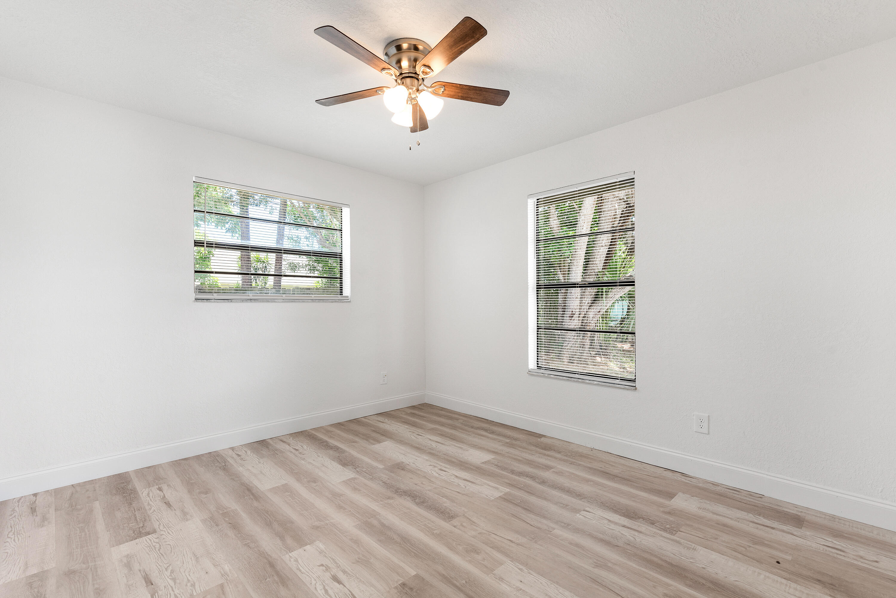 5629 Southeast Collins Avenue Stuart, FL 34997 - Photo 13 of 39 an empty room with wooden floor ceiling fan and windows