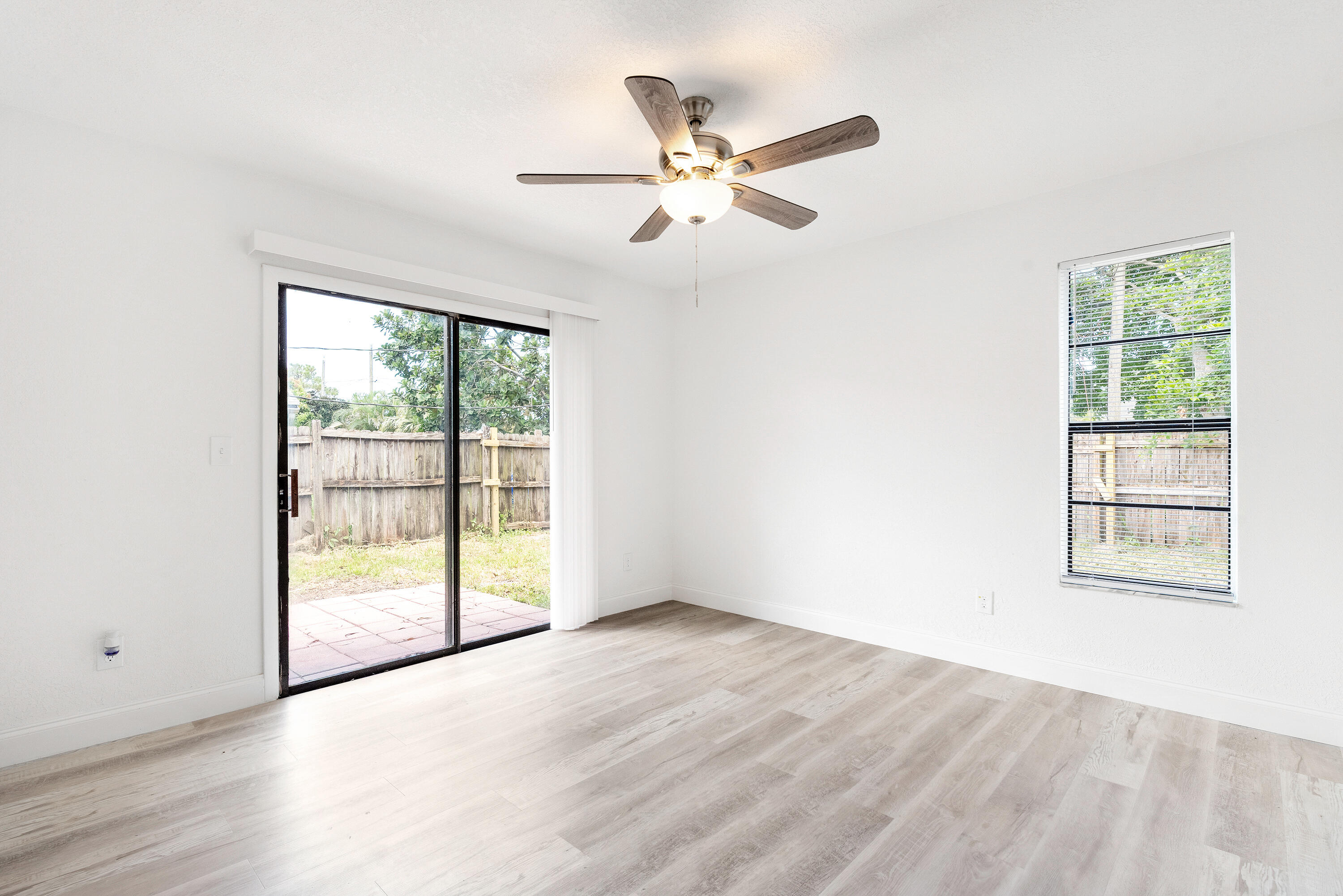5629 Southeast Collins Avenue Stuart, FL 34997 - Photo 21 of 39 an empty room with wooden floor fan and windows
