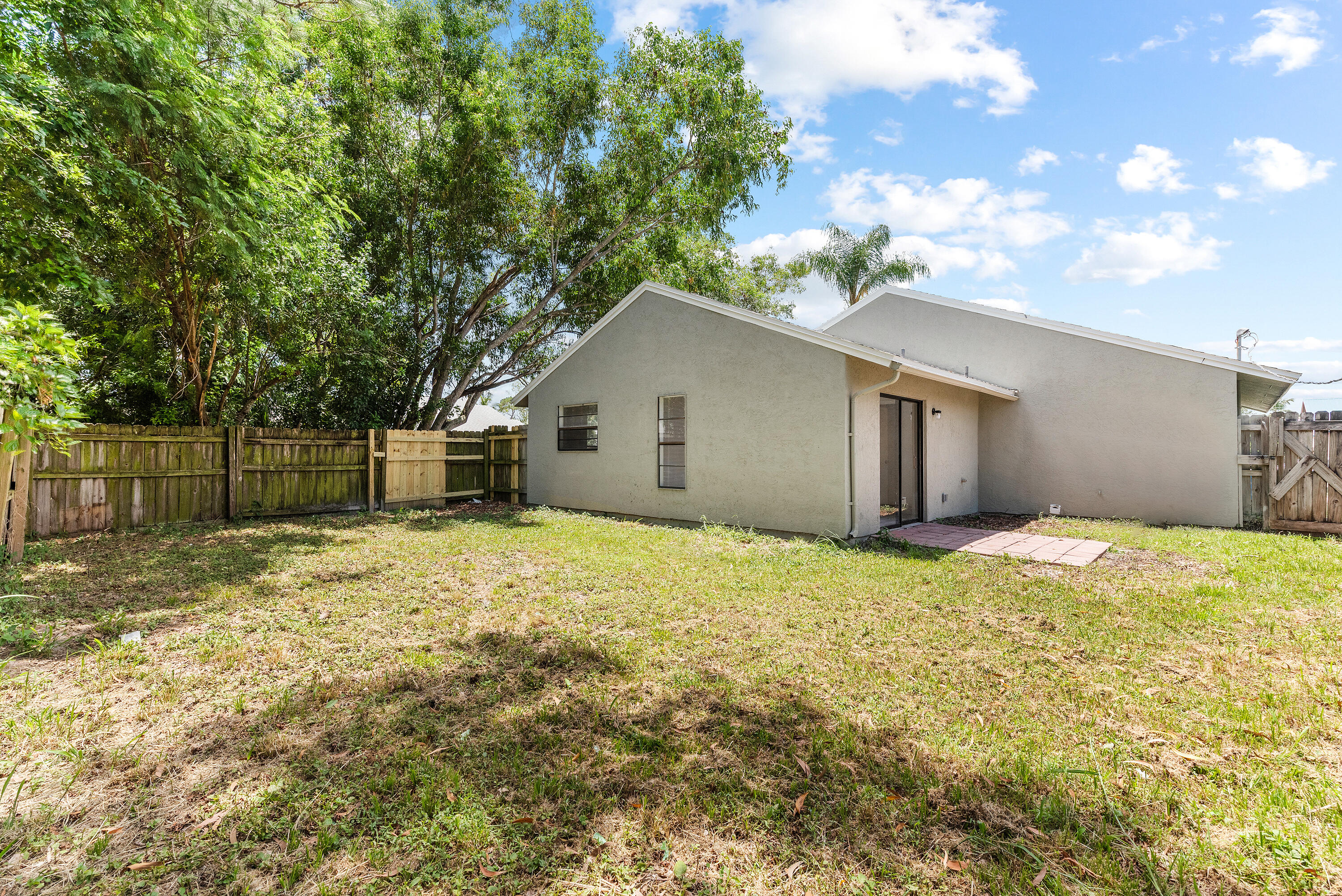 5629 Southeast Collins Avenue Stuart, FL 34997 - Photo 25 of 39 a yellow and white house in front of a yard with wooden fence