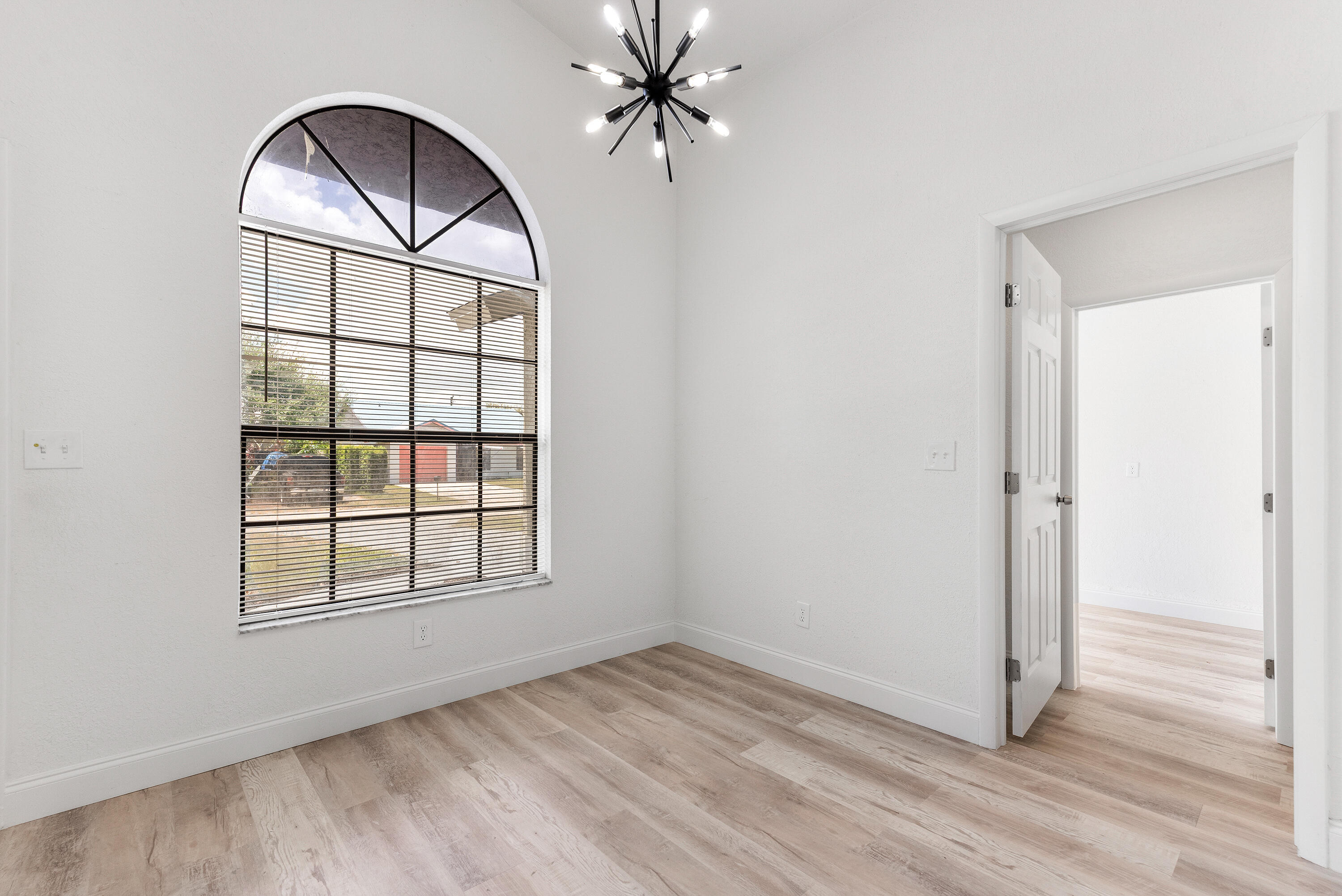 5629 Southeast Collins Avenue Stuart, FL 34997 - Photo 28 of 39 an empty room with wooden floor chandelier and windows