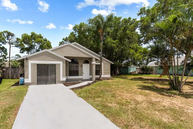 a front view of a house with a yard and trees