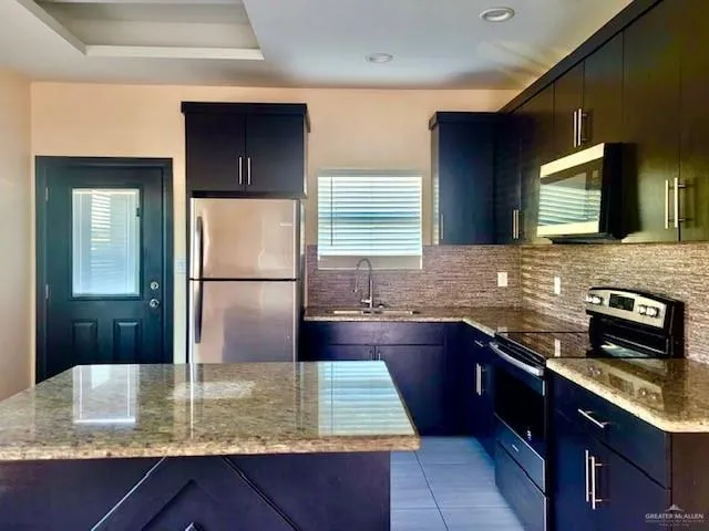 a kitchen with kitchen island granite countertop a sink stove and refrigerator