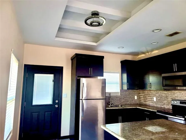 a kitchen with stainless steel appliances granite countertop a sink a refrigerator and a stove