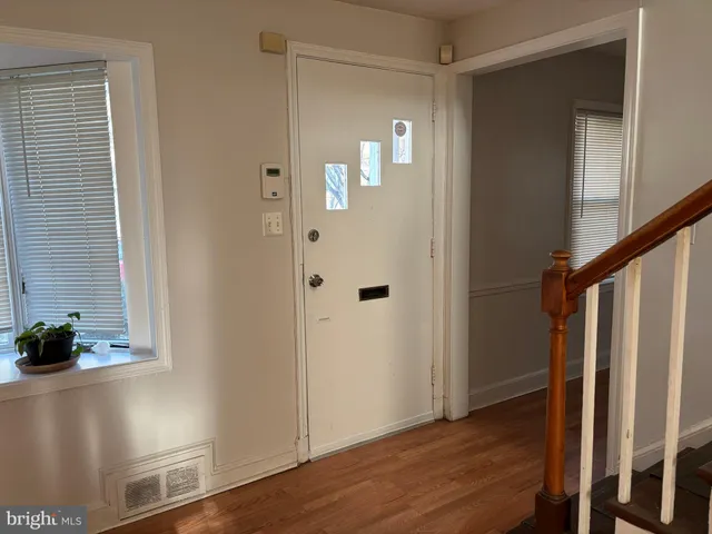 a view of an empty room with wooden floor fireplace and a window
