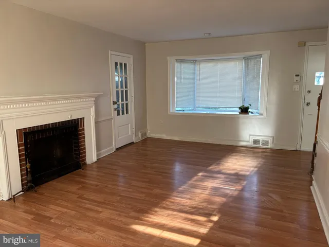an empty room with wooden floor a fireplace and windows
