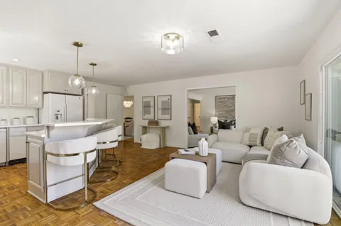 a living room with furniture kitchen view and a chandelier