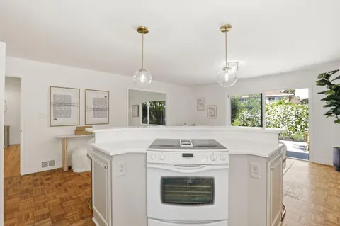 a kitchen with kitchen island a stove a oven a counter space and a sink