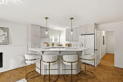 a kitchen with stainless steel appliances a dining table chairs and white cabinets
