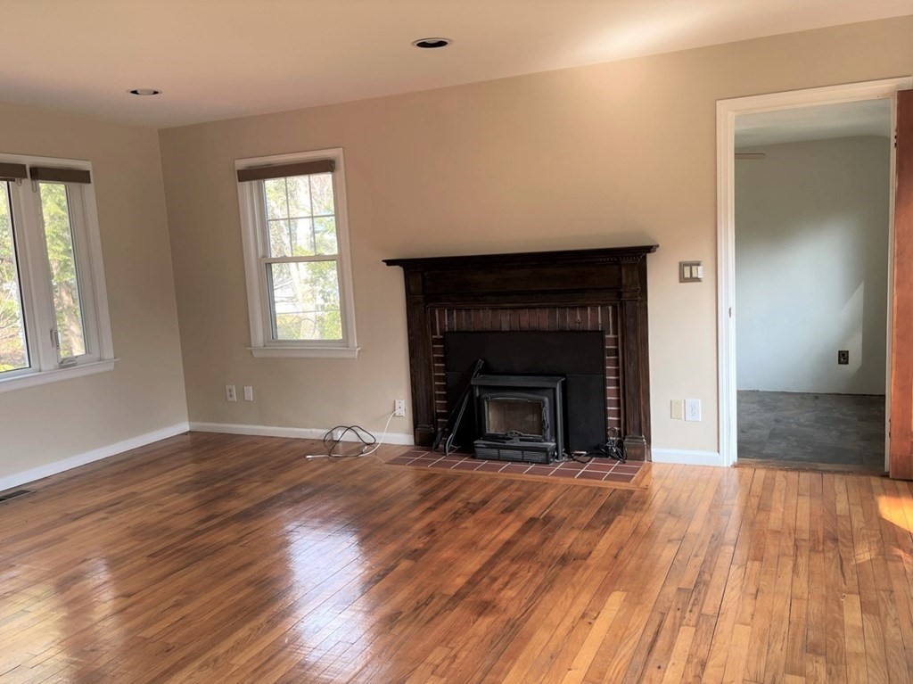 20 Howell Road Sudbury, MA 01776 - Photo 5 of 39 an empty room with wooden floor a fireplace and windows