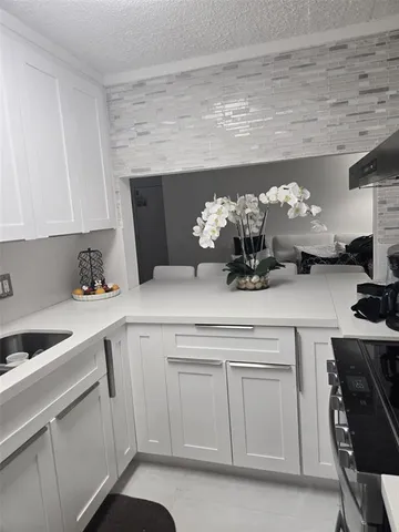 a kitchen with a sink dishwasher and white cabinets