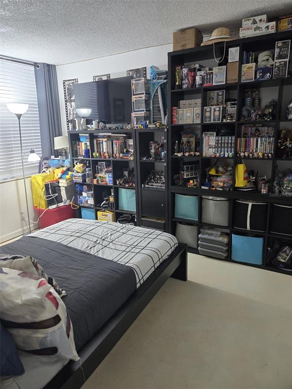 9410 Live Oak Place, Unit 103 Davie, FL 33324 - Photo 26 of 49 a bedroom with a bed a table and a book shelf