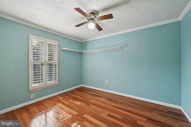 a view of a room with a ceiling fan and wooden floor