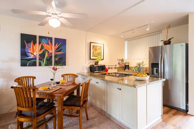 a kitchen with stainless steel appliances granite countertop a dining table chairs and a refrigerator