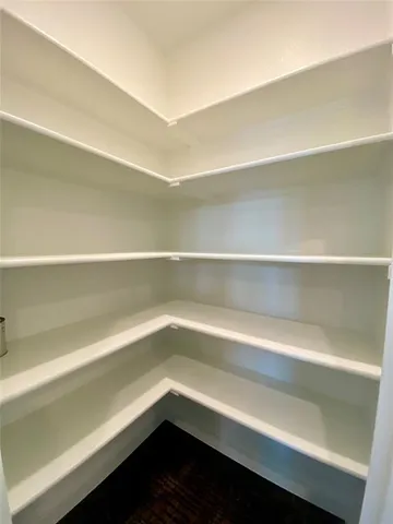 a view of an empty room with wooden floor fireplace and a window