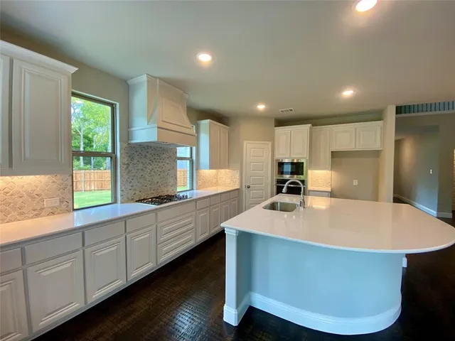 a large kitchen with stainless steel appliances granite countertop a sink a stove and a refrigerator