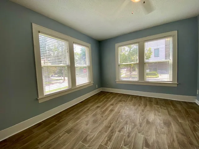 a view of an empty room with wooden floor and a window