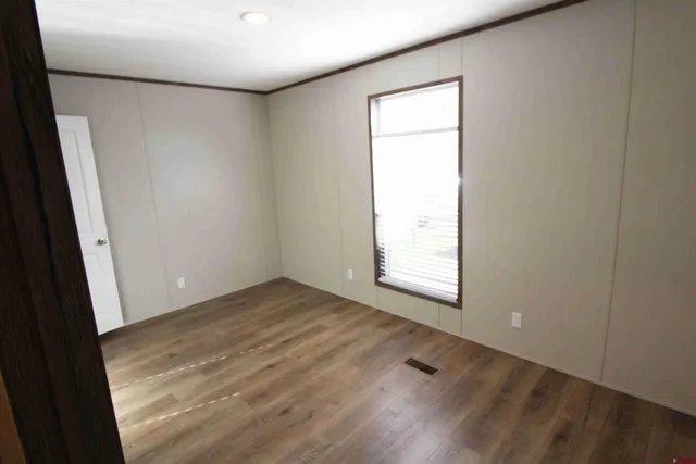 an empty room with wooden floor and windows with curtains