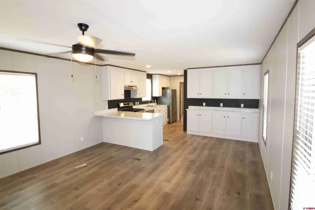 a kitchen with granite countertop a refrigerator a stove a microwave and white cabinets with wooden floor