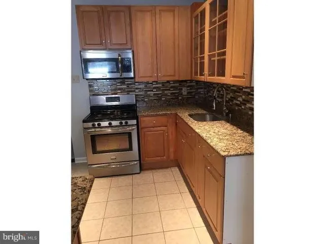 a kitchen with granite countertop a stove top oven and cabinets