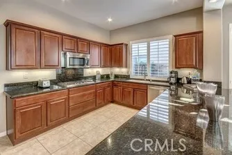 a large kitchen with stainless steel appliances granite countertop a stove top oven a sink a dining table and chairs
