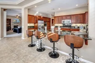 a kitchen with stainless steel appliances kitchen island granite countertop a sink a refrigerator and chairs