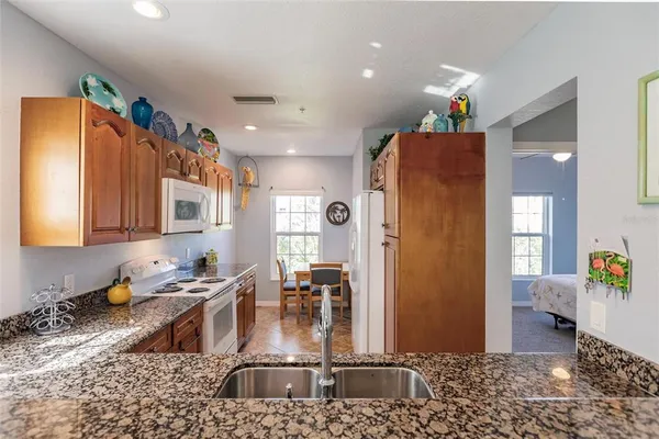 a kitchen with stainless steel appliances granite countertop a refrigerator a stove and a sink