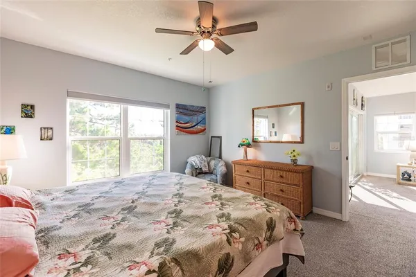 a bedroom with a large bed and a chandelier fan