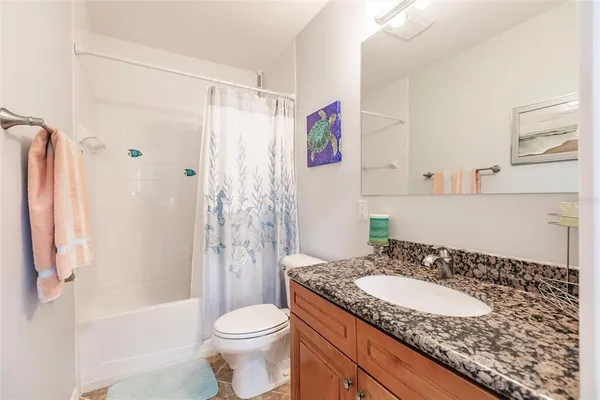 a bathroom with a granite countertop sink toilet and shower