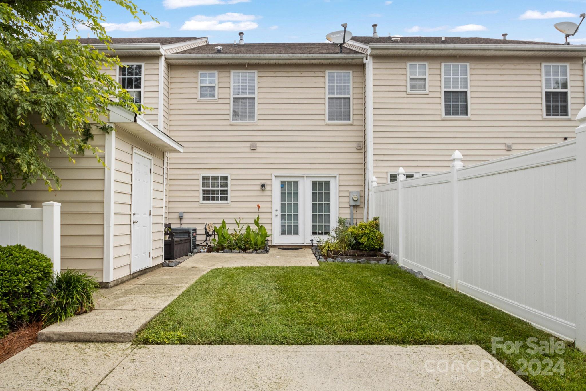 6031 Creft Circle Indian Trail, NC 28079 - Photo 20 of 28 a backyard of a white house with potted plants and a bench