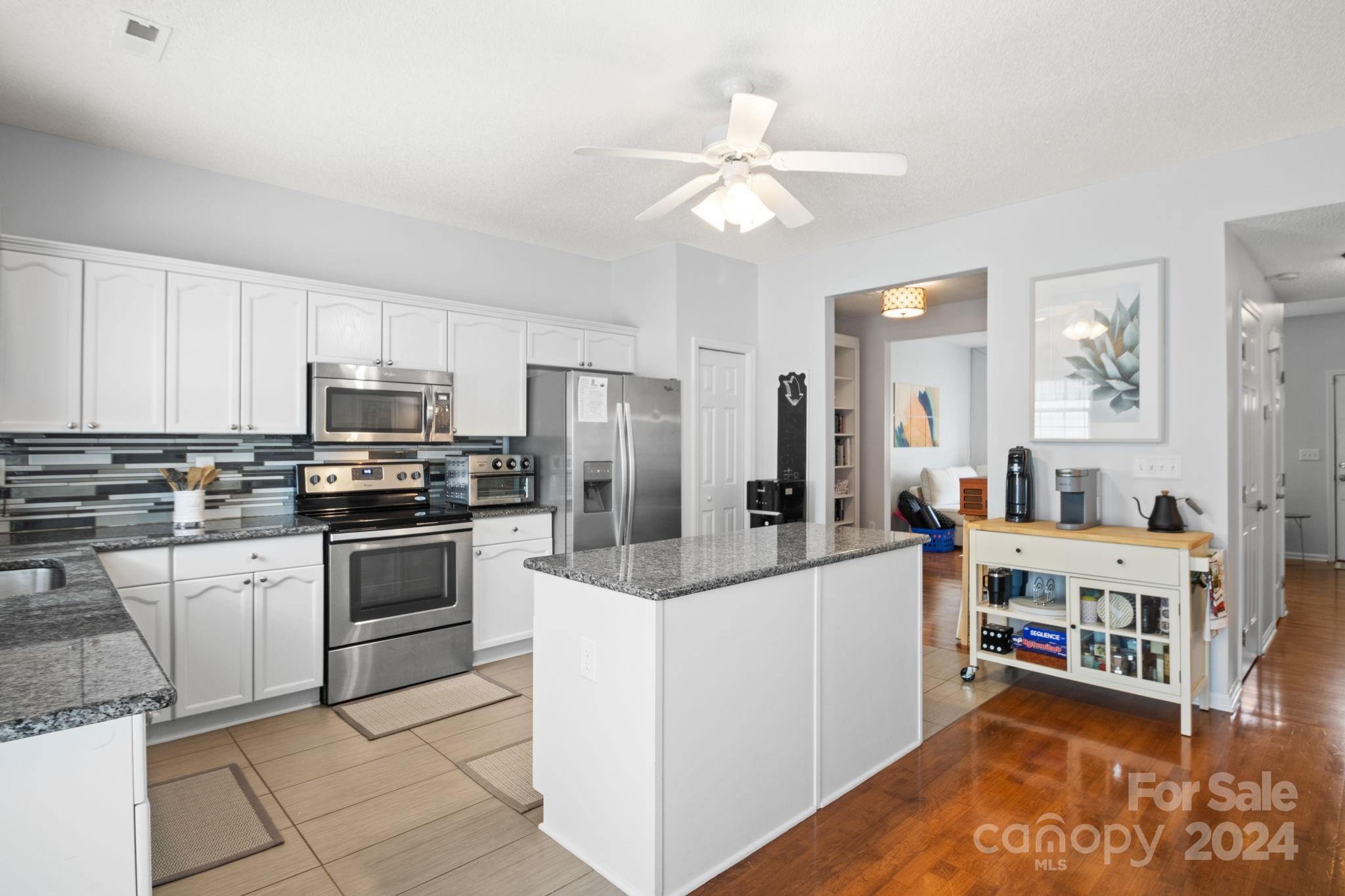 6031 Creft Circle Indian Trail, NC 28079 - Photo 8 of 28 a kitchen with stainless steel appliances kitchen island granite countertop a refrigerator and a stove top oven